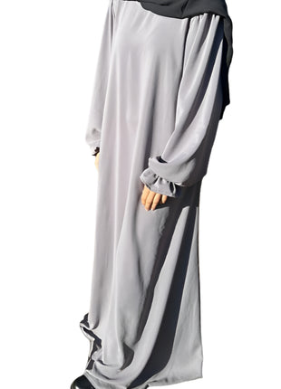 Person wearing a long gray dress with a hood in an outdoor setting